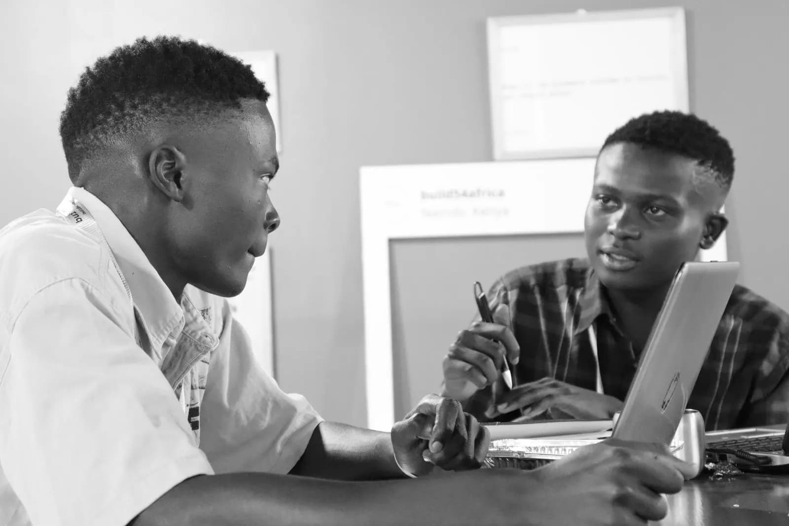 Two builders in conversation across a laptop.